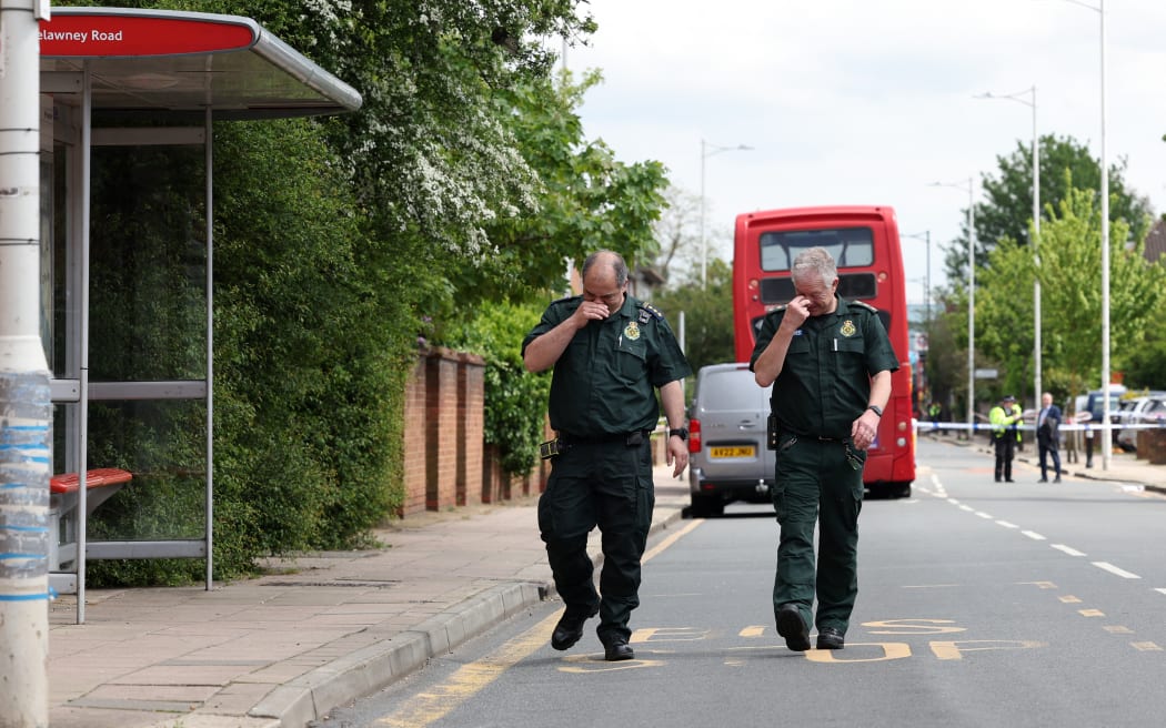 Paramedics walk behind a Police Cordon at a crime scene in Hainault, east of London on April 30, 2024, where a 36-year-old man wielding a sword was arrested following an attack on members of the public and two police officers. A 13-year-old boy died on Tuesday after five people, including two police officers, were wounded by a man wielding a sword in east London, police said. "It's with great sadness that one of those injured in this incident, a 13-year-old boy, has died from their injuries," Chief Superintendent Stuart Bell, from the Metropolitan Police, told reporters. (Photo by Adrian DENNIS / AFP)