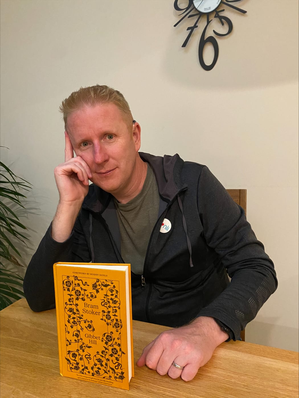 Brian sits at a dining room table with the print edition of Bram Stoker's Gibbet Hill.