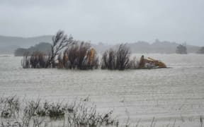 Heavy machinery caught in floodwater at the Wairoa River mouth, Wednesday 26 June 2024. The digger is used to open up a channel in the bar to let floodwater escape more quickly.