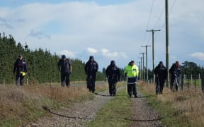 Police investigators canvass Main Rakaia Road, where the woman's body was found.
