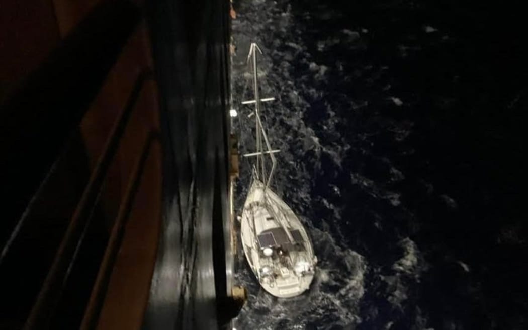 The yacht carrying three New Zealanders who were seriously injured after a being hit by a broken mast, next to to the Australian cruise ship that provided assistance.