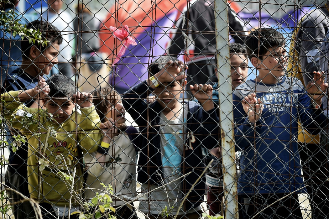 Children stand behind a fence inside the Moria migrant camp transformed in police-run detention facility in Mytilene, on Lesbos island on April 3, 2016.