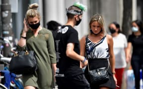 People wear protective face masks as they walk in the city center of Antwerp, Belgium, on July 27, 2020.