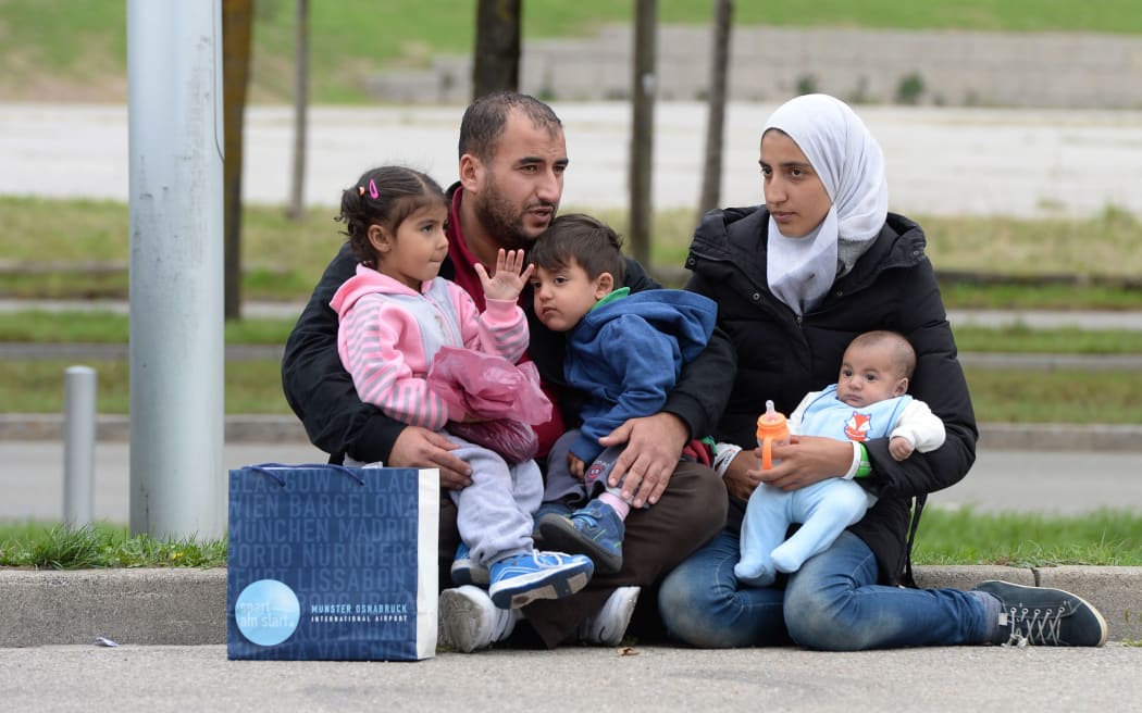 A refugee family from Syria waits in front of a exhibition hall at the Munich fairground that serves as makeshift shelter for migrants.