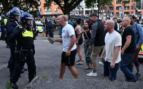 A protester holding a piece of concrete walks towards riot police as clashes erupt in Bristol on 3 August 3, 2024 during the 'Enough is Enough' demonstration held in reaction to the fatal stabbings in Southport on July 29. UK police prepared for planned far-right protests and other demonstrations this weekend, after two nights of unrest in several English towns and cities following a mass stabbing that killed three young girls. (Photo by JUSTIN TALLIS / AFP)