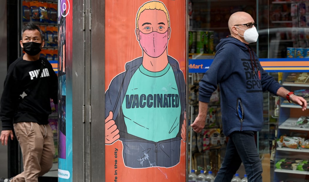 People walk past a poster encouraging vaccinations in Melbourne on September 30, 2021 as the city grapples with a surge in Covid-19 infections recording 1,438 cases, the largest daily total since the start of the pandemic, linked to ongoing street protests and illegal gatherings and house parties