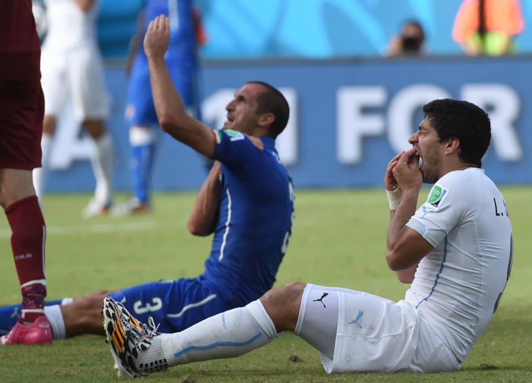 Uruguay's Luis Suarez, right, acts hurt as Giorgio Chiellini claims Suarez has bitten him on the shoulder.