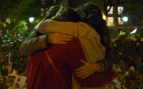 People hug in front of a memorial set up near the Bataclan theatre in Paris.
