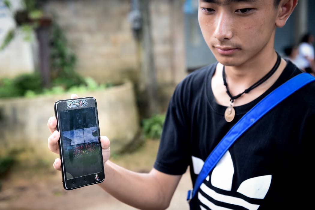 Thananchai Saengtan, 15, shows the camera a photo of his missing friends, at a football pitch near Tham Luang cave, at the Khun Nam Nang Non Forest Park in Chiang Rai province on July 1, 2018.