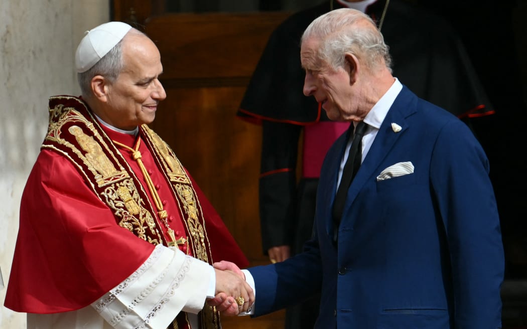 Pope Leo XIV shakes hands with Britain's King Charles III in San Damaso courtyard during a State visit to the Vatican on October 23, 2025.