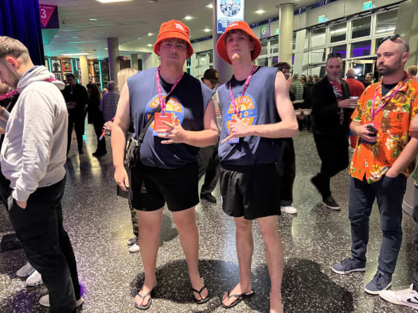 Two young men in bucket hats and sleeveless Speight's t-shirts.