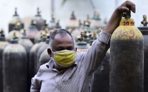 A man waits to refill a medical oxygen cylinders for a Covid-19 coronavirus patient at an oxigen refile station in Allahabad on April 20, 2021 (Photo by SANJAY KANOJIA / AFP)