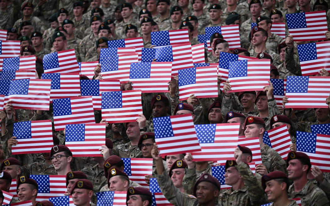 Members of the US army hold up US flags as the US president speaks at Fort Bragg, a US Army military installation, near Fayetteville, North Carolina, on June 10, 2025. (Photo by Brendan SMIALOWSKI / AFP)