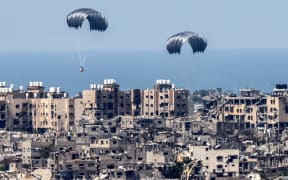This picture taken from Israel's southern border with the Gaza Strip shows parachutes of humanitarian aid dropping over the besieged Palestinian territory on March 26, 2024, amid the ongoing conflict between Israel and the militant group Hamas. Seven people have drowned in the Mediterranean trying to reach aid airdropped into Gaza, the Hamas-run territory's health ministry said on March 26. Six people were also injured in the previous day's airdrop, the ministry said. Hamas said a total of 18 people have now been killed in drownings or stampedes since aid airdrops to the starving north of the besieged territory began. (Photo by JACK GUEZ / AFP)