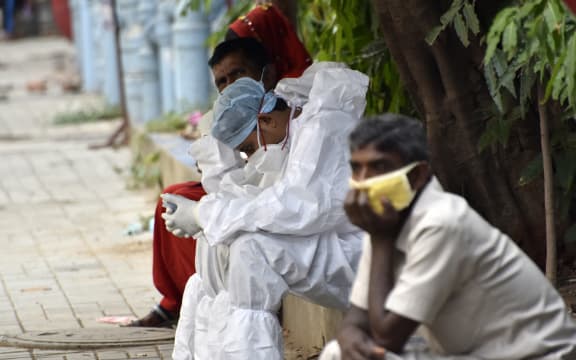 A health worker wearing a PPE Kit, rests on a foothpath of a government hospital during coronavirus emergency in Kolkata, India.