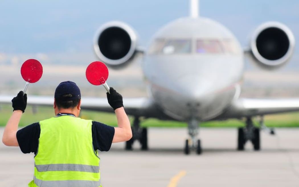 An air traffic controller guides a plane on a runway.