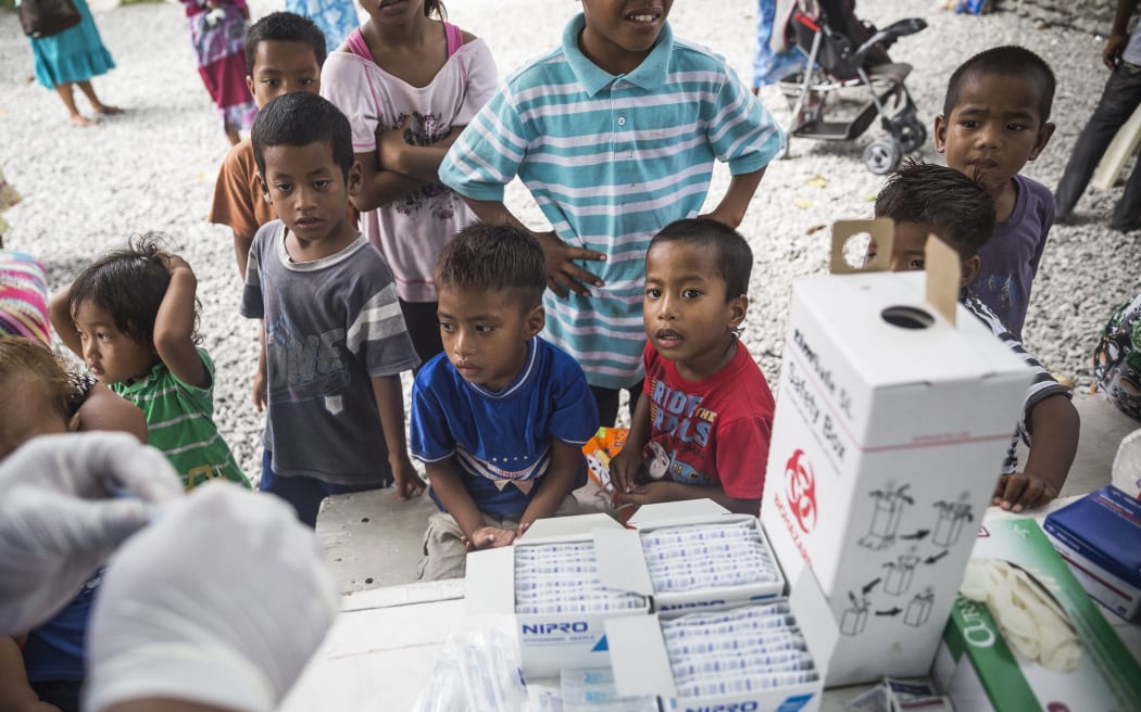 Children watching a member of the Outreach Immunisation Team of Majuro Hospital, preparing immunisation shots in the Marshall Islands.