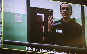 A screen shows jailed Kremlin critic Alexei Navalny as he arrives to listen to a hearing on an appeal lodged against a court decision to jail him for 19 years in a maximum security prison on extremism-linked charges, at a court in Moscow on September 26, 2023. Navalny was Russia's loudest opposition voice over the last decade and galvanised huge anti-government rallies before he was jailed in 2021 on fraud charges that his allies at home and abroad said were punitive. (Photo by TATYANA MAKEYEVA / AFP)