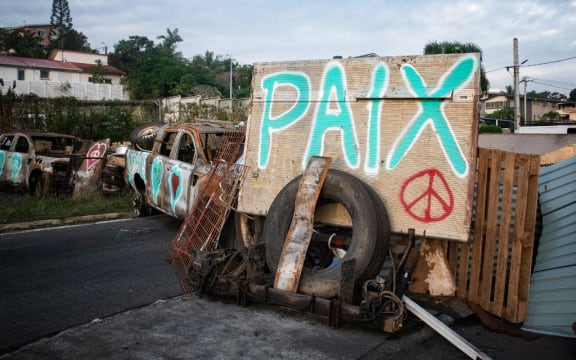 A photograph shows a roadblock set up by residents of Noumea's Sixth Kilometer district, bearing a handwritten message which reads as 'Peace' in Noumea, France's Pacific territory of New Caledonia on May 19, 2024. French forces smashed through about 60 road blocks to clear the way from conflict-stricken New Caledonia's capital to the airport but have still not reopened the route, a top government official said on May 19, 2024. (Photo by Delphine Mayeur / AFP)
