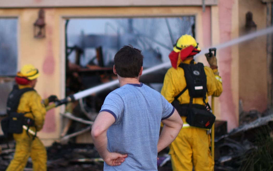 A resident looks at his home after one of nine wildfires destroyed homes in Southern California