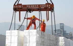 Workers loading products for export onto a ship at Lianyungang, in China's eastern Jiangsu province, 7 June 2020.