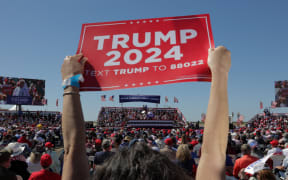 A supporter of former US President Donald Trump holds a "Trump 2024" sign at a 2024 election campaign rally in Waco, Texas, March 25, 2023. - Trump held the rally  at the site of the deadly 1993 standoff between an anti-government cult and federal agents. (Photo by Shelby Tauber / AFP)
