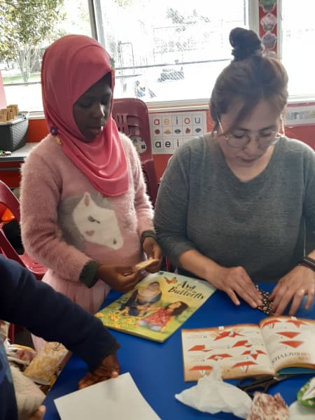 Tutor Laura helps a student with her origami.