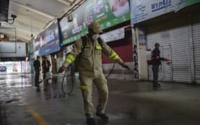 Cleaning personnel spray disinfectant at the "Central de Abasto" wholesale market, the biggest food supply central in Mexico City, on March 24, 2020 to fight against the coronavirus Covid-19 outbreak.