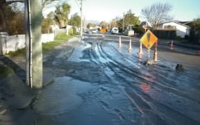 Silt and water produced by liquefaction covers a street in Avonside, Christchurch.
