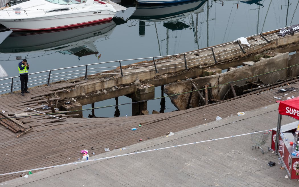 A police investigator inspects the seafront platform in Vigo on August 13, 2018 after a section of a wooden promenade suddenly collapsed.