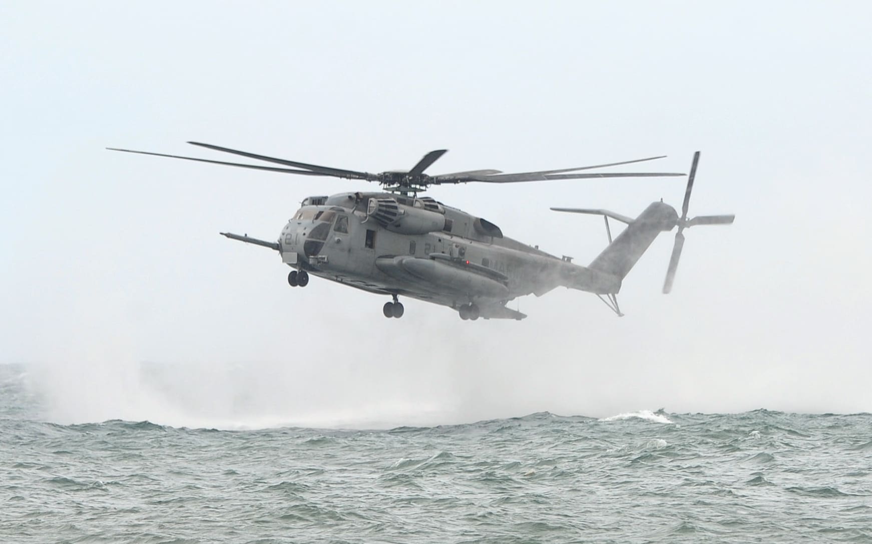 A CH-53E Super Stallion heavy lift assault helicopter hovers above the sea.