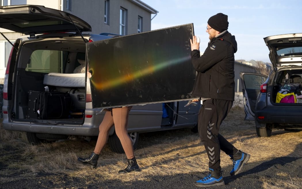 This photo taken on November 13, 2023 shows inhabitants carrying belongings from their homes to a vehicle in Grindavik, southwestern Iceland, following earthquakes. The southwestern town of Grindavik -- home to around 4,000 people -- was evacuated in the early hours of November 11 after magma shifting under the Earth's crust caused hundreds of earthquakes in what experts warned could be a precursor to a volcanic eruption.  The seismic activity damaged roads and buildings in the town situated 40 kilometres (25 miles) southwest of the capital Reykjavik, an AFP journalist saw. (Photo by Kjartan TORBJOERNSSON / AFP) / Iceland OUT