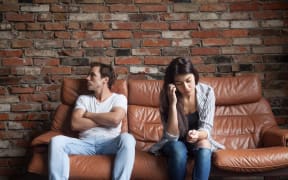 Frustrated upset couple in quarrel not talking after fight, offended stubborn insulted jealous man sitting silent on sofa at home with sad depressed disappointed woman, marriage relationships problem