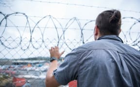 Prisoner "Michael" stands behind a fence