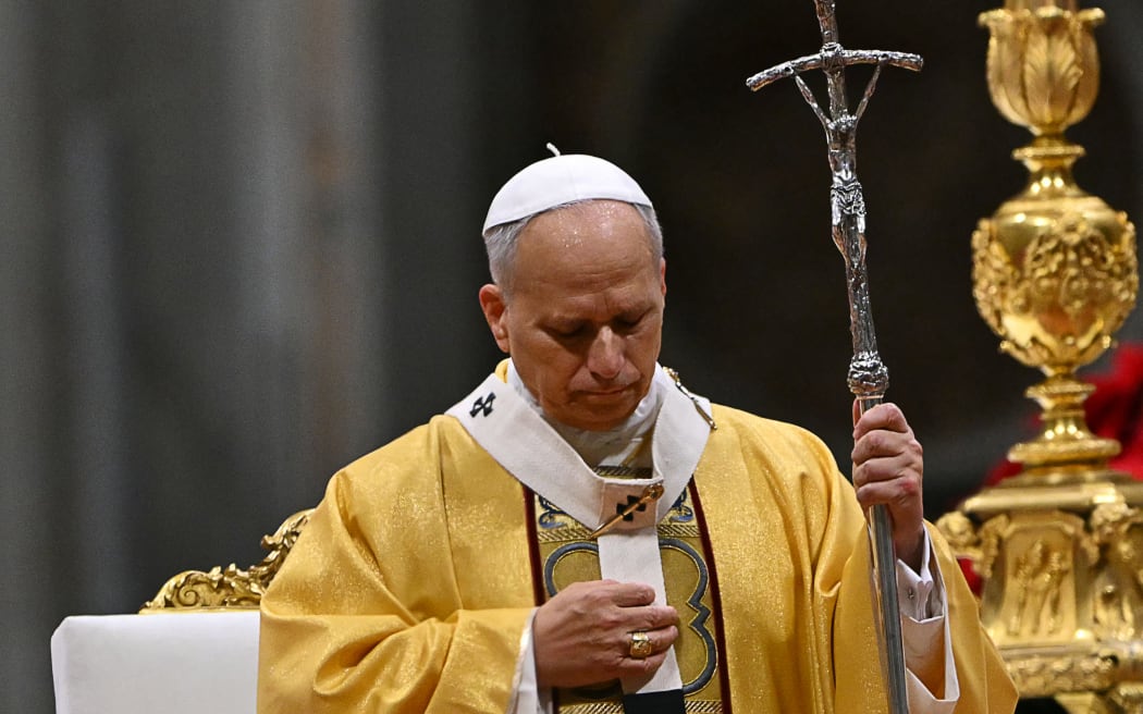 Pope Leo XIV holds a crucifix, while performing the Christmas Eve mass at St Peter's Basilica in the Vatican on 24 December, 2025.