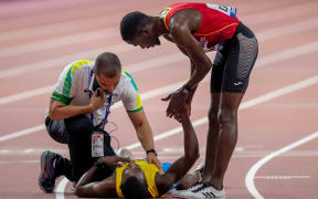Braima Suncar Dabo of Guinea-Bissau checks on Aruba's Jonathan Busby after he helped him up the finishing straight of the men's 5000m.