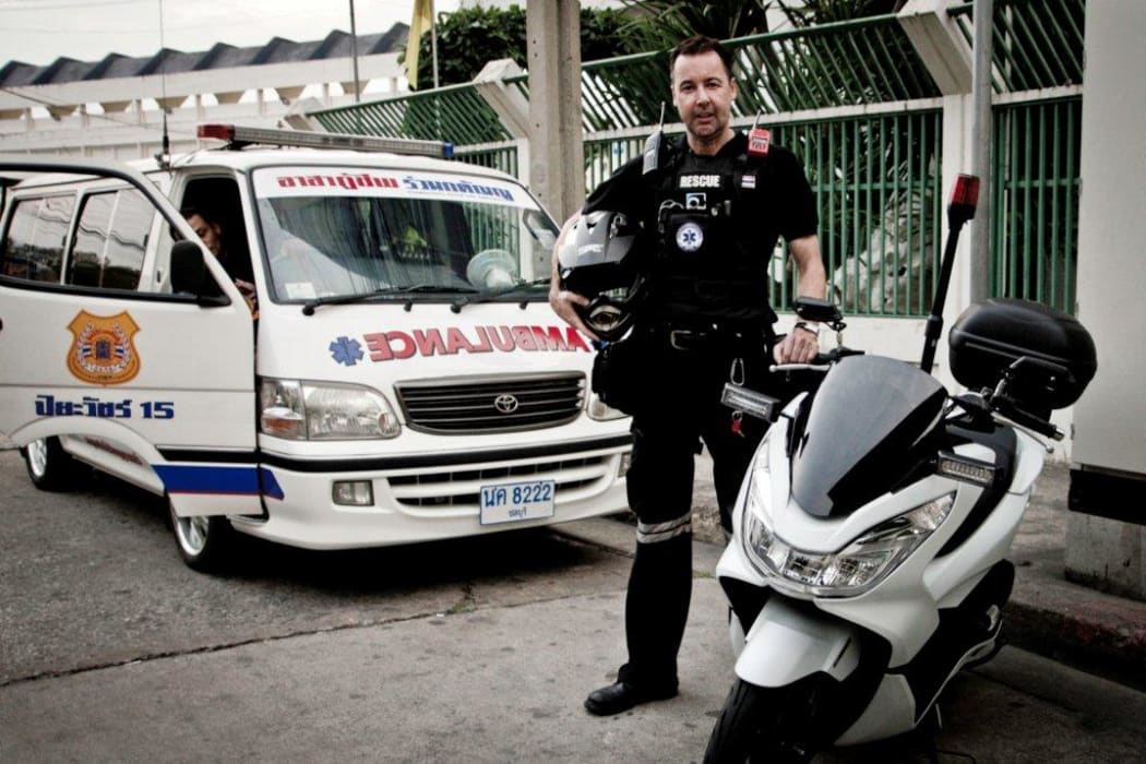 Marko standing with his emergency motorcycle and his fellow volunteer’s ambulance van.