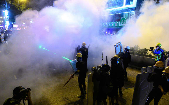 Protesters stand as police officers fire tear gas during a protest in Tsim Sha Tsui district of Hong Kong.
