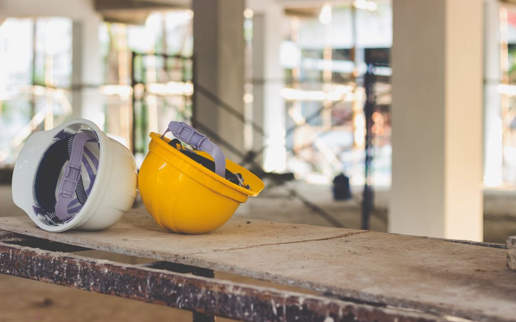 Yellow and white helmets are placed on the wooden table inside the construction area.