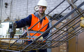 A factory worker attaches steel mesh at a concrete reinforcement factory.