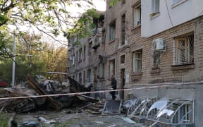 A local resident takes his belongings out of a damaged residential building after a drone attack in Zaporizhzhia on May 2, 2025, amid the Russian invasion of Ukraine. Russian strikes wounded more than 30 people in Ukraine overnight, officials said on May 2, 2025, a day after Kyiv and Washington signed a landmark minerals deal. (Photo by STRINGER / AFP)