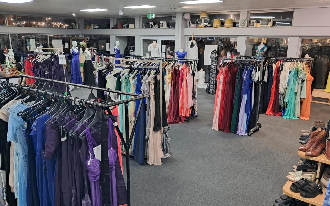 Photo shows a setup inside an op shop, with racks and racks of ball dresses on display.