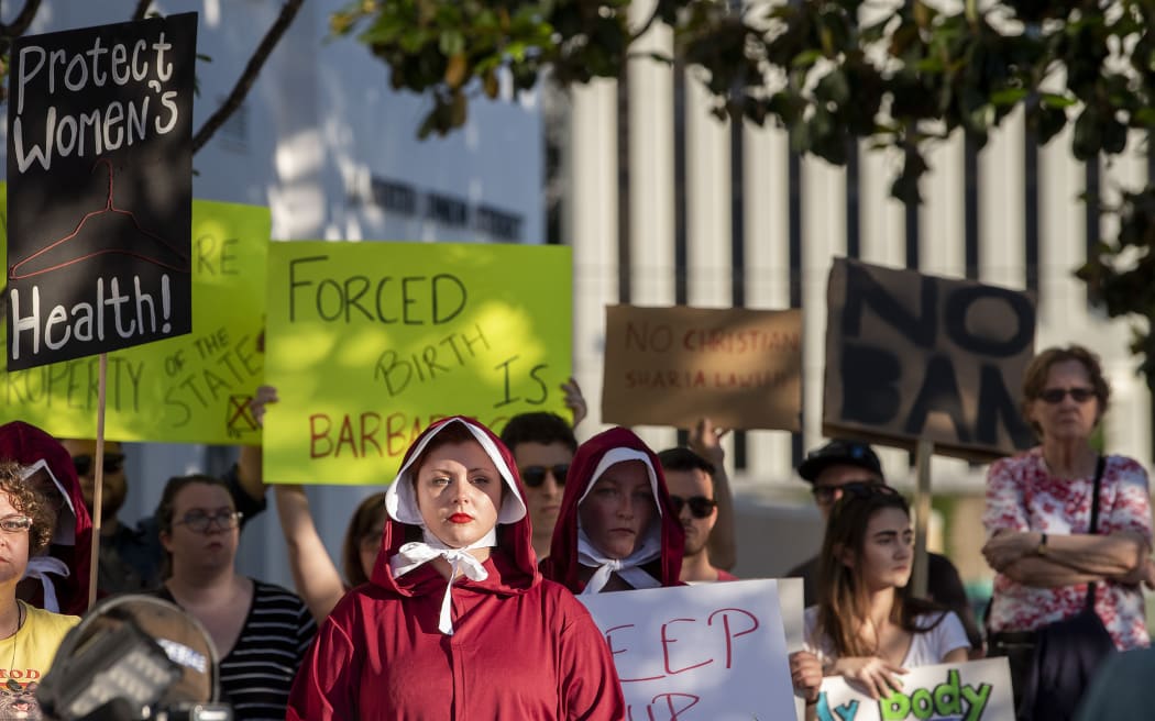 Margeaux Hartline, dressed as a handmaid, protests against the ban.