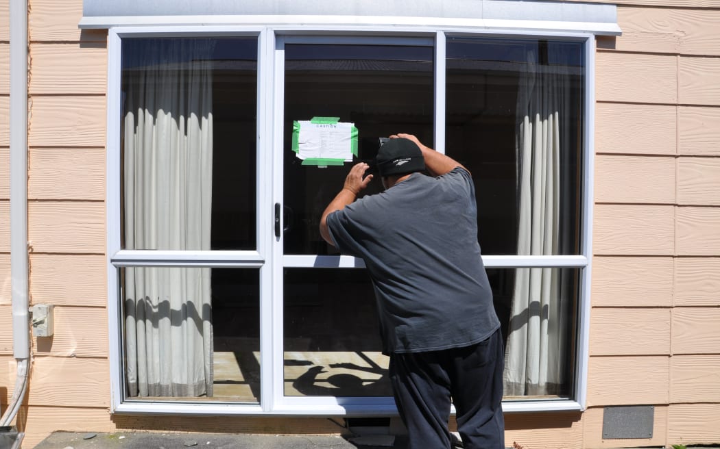 Pat Koti looks into his yellow-stickered rental home that was damaged during the floods in Westport.