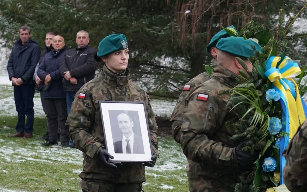 A Polish soldier carries a picture of one of two victims of a missile that hit a southeastern Polish village near the border with Ukraine, during his funeral in Przewodow on November 19, 2022. - The explosion of the missile occurred on November 15, 2022 as Russia targeted Ukraine with a massive attack on civilian infrastructure which left millions of households without power. Russian missiles hit cities across Ukraine, including Lviv near the Polish border. (Photo by JANEK SKARZYNSKI / AFP)