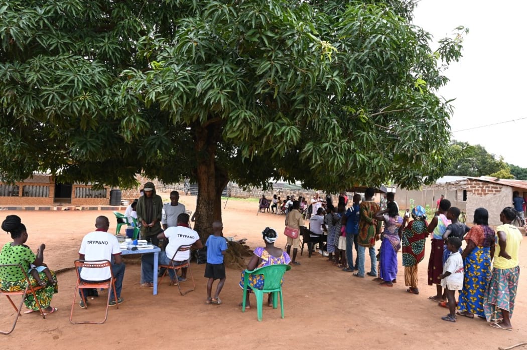 People queue in line as they wait to take part in an Human African Trypanosomiasis, also known as sleeping sickness, screening in the village of Paanenefla near Sinfra, Ivory Coast