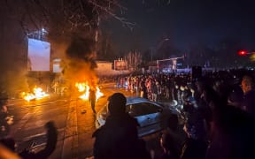 Iranians gather while blocking a street during a protest in Tehran, Iran on January 9, 2026. The nationwide protests started in Tehran's Grand Bazaar against the failing economic policies in late December, which spread to universities and other cities, and included economic slogans, to political and anti-government ones. (Photo by MAHSA / Middle East Images via AFP)