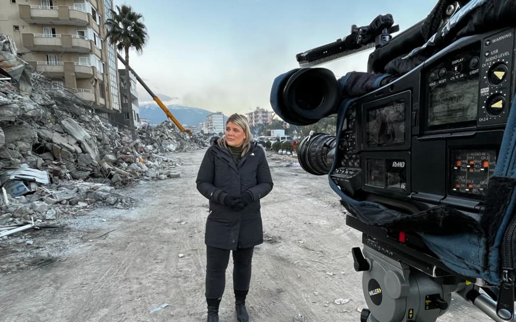 Correspondent Lisette Reymer standing in the rubble for a morning live cross after a night of camping out in a car amid constant earthquake aftershocks in Turkey.
