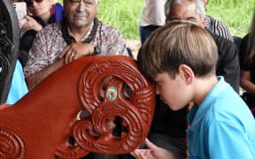 A Kerikeri Primary School student hongis the freshly unveiled waka.