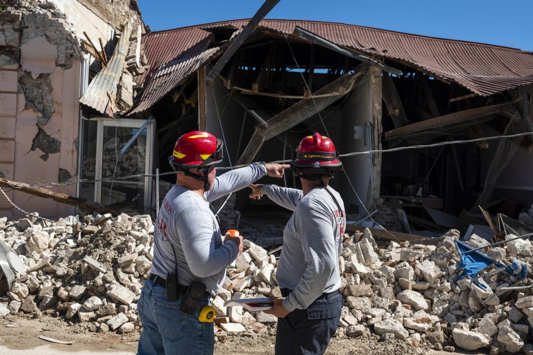Two firefighters survey a collapsed building after an earthquake hit the island in Guanica, Puerto Rico after a strong earthquake struck early on 7 January, followed by major aftershocks.